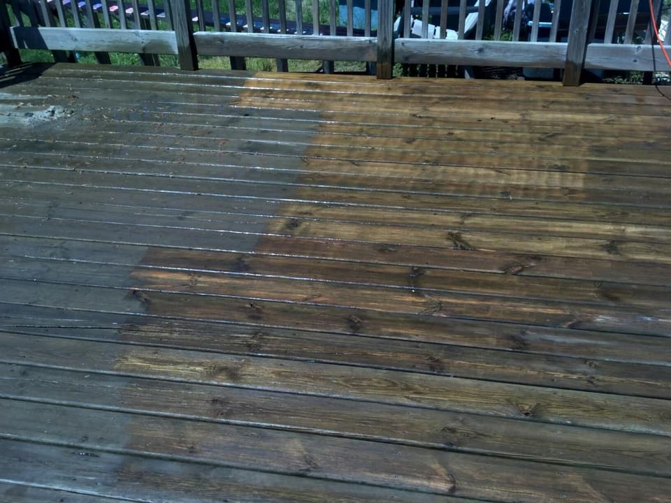 Wood deck partway through cleaning: the washed boards are bright brown, the rest still gray and weathered